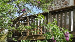 A stone building with a wooden balcony and a climbing plant with purple flowers.