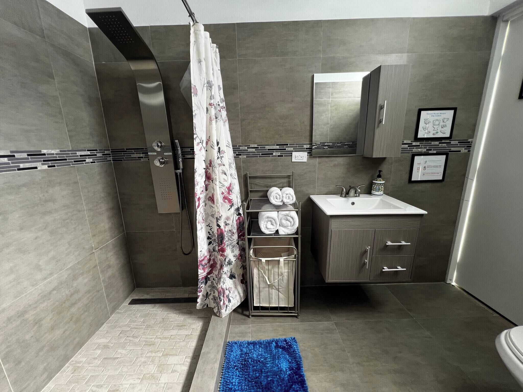 A modern bathroom with a shower, a sink, and a toilet.