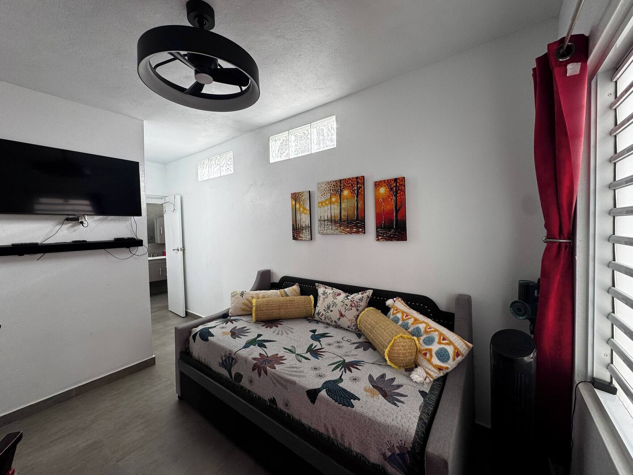 A modern bedroom with a bed, a TV mounted on the wall, and artwork on the walls.