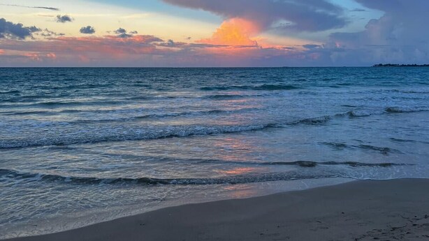 A beach with footprints leading to the water, a clear sky, and a sunset. - Charming apartment 5' walk to the beach (Carolina)