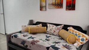 A modern living room with a large sofa, decorative pillows, and three paintings on the wall. - Charming apartment 5' walk to the beach (Carolina)