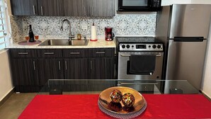A modern kitchen with dark wood cabinets, a stainless steel refrigerator, a microwave, and a gas stove. - Charming apartment 5' walk to the beach (Carolina)