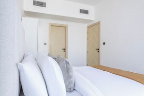 A hotel room with a bed, two doors, and a white wall. - Bloomfields 1BR in Binghatti Avenue-Jaddaf (Dubai)