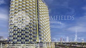 A high-rise building with a distinctive geometric facade, multiple balconies, and a prominent signage at the top. - 122 Bloomfields Cozy1BR Binghatti Avenue (Dubai)