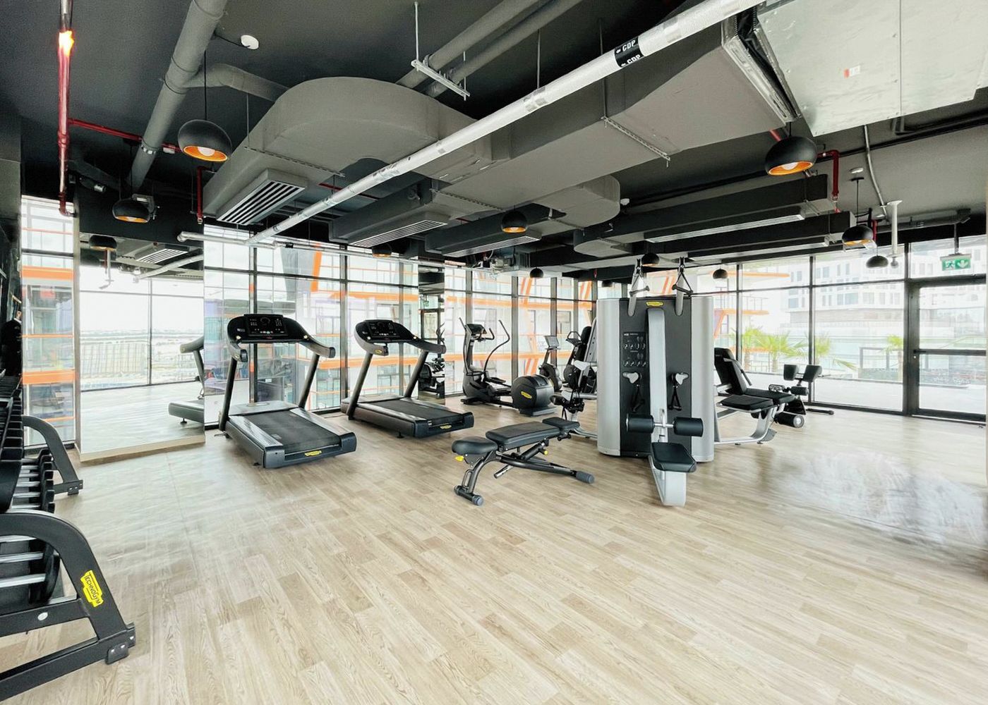 Un gimnasio con cintas de correr, máquinas de pesas y un ventanal grande.