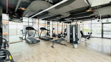 Ein Fitnessstudio mit Laufbändern, Krafttrainingsgeräten und einem großen Fenster.