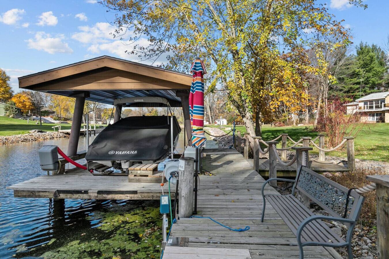 A dock with a covered seating area, a Yamaha boat, and a wooden bench.