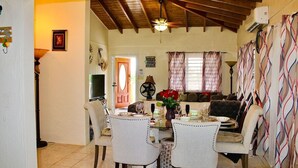 Un'area pranzo con soffitto in legno, un tavolo imbandito per quattro persone e un divano sullo sfondo.