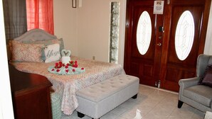 Una camera da letto con un letto, una panca, una sedia e una porta con pannelli di vetro.