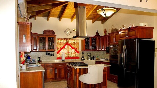Una cucina con mobili in legno, un frigorifero nero, un fornello e una sedia.