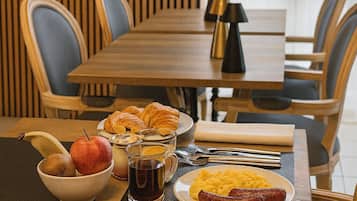 A dining table set with breakfast items, including croissants, fruit, and plates of food.