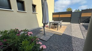 Een terras met een tafel en stoelen, omgeven door grind en planten.