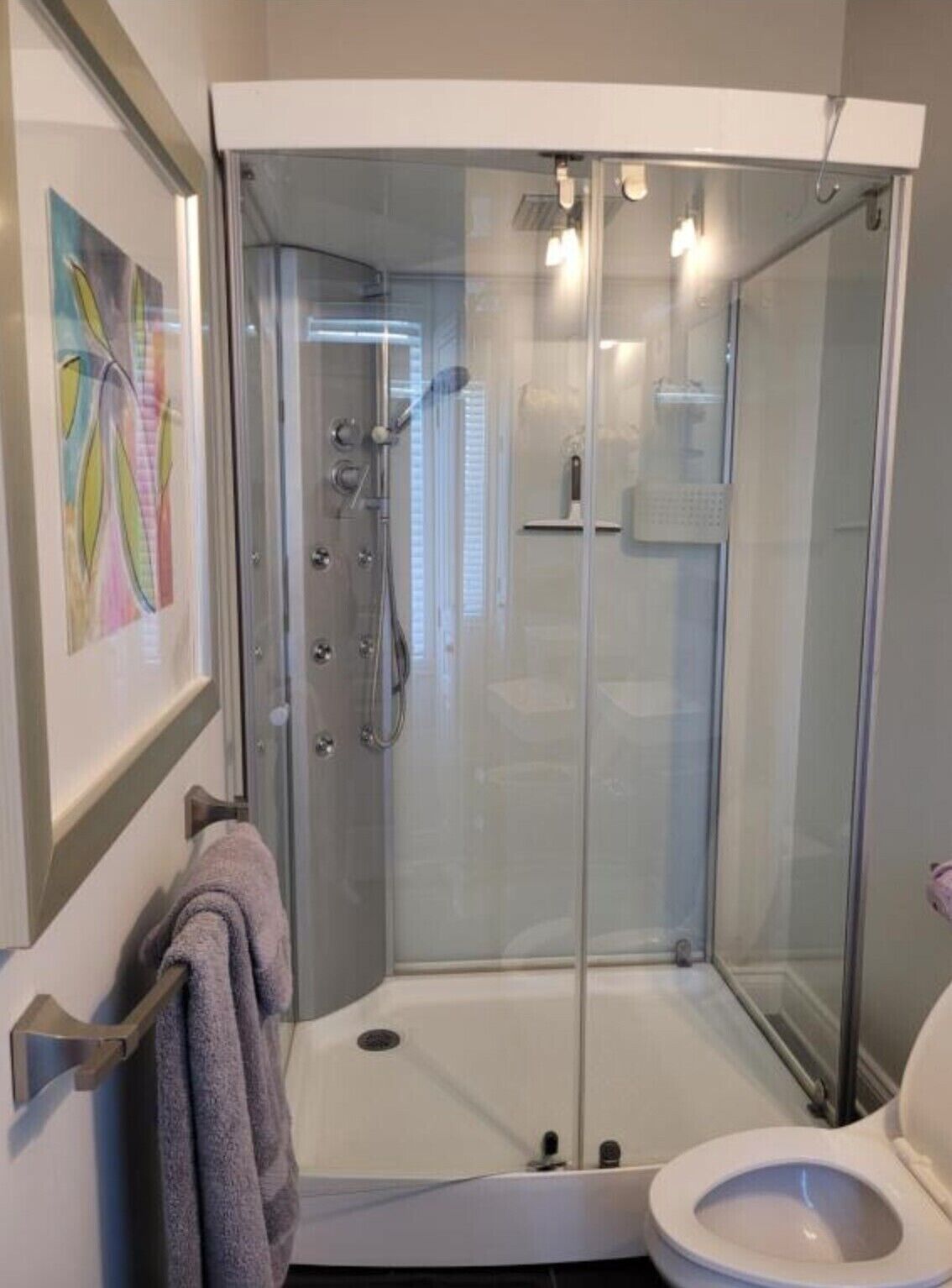 Un baño moderno con ducha de vidrio, inodoro y toallero.