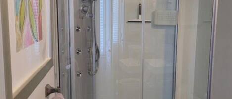 Un baño moderno con ducha de vidrio, inodoro y toallero.