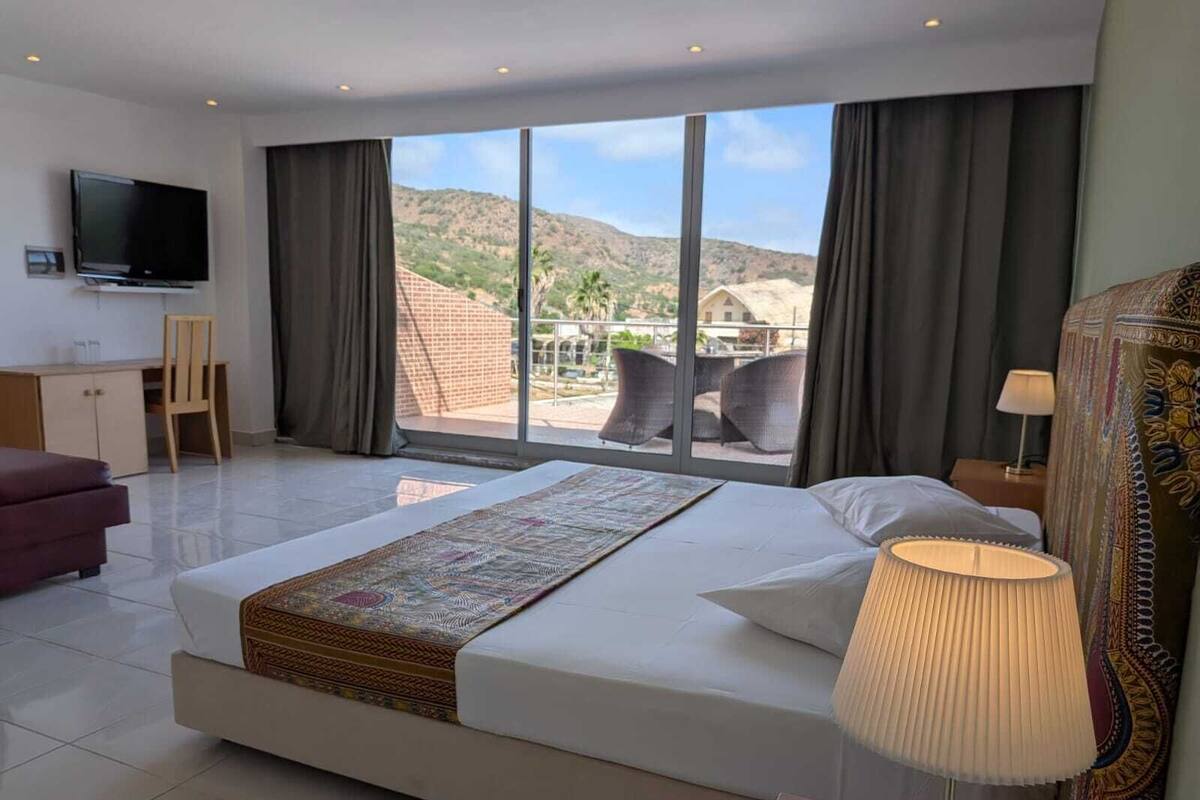 Une chambre d’hôtel avec un grand lit, un bureau, une télévision et une vue sur les montagnes.