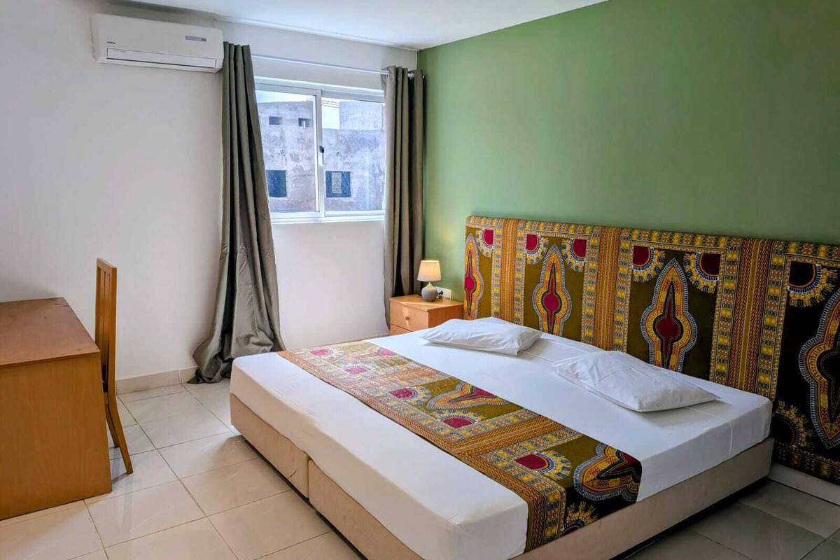 Une chambre d’hôtel avec un lit, un bureau et une fenêtre avec des rideaux.