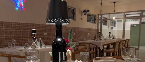 A dining table set with wine glasses, a bottle of Azethin Syrah, and a menu.