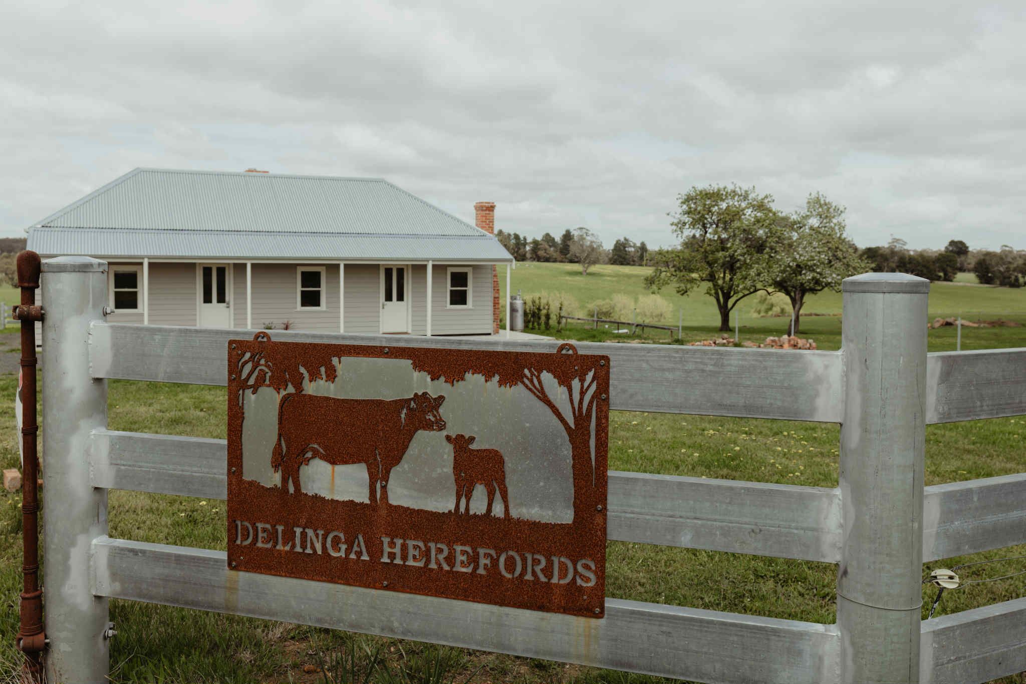 Ein rustikaler Holzzaun mit einem Schild, auf dem 'Delingaherefords' steht.