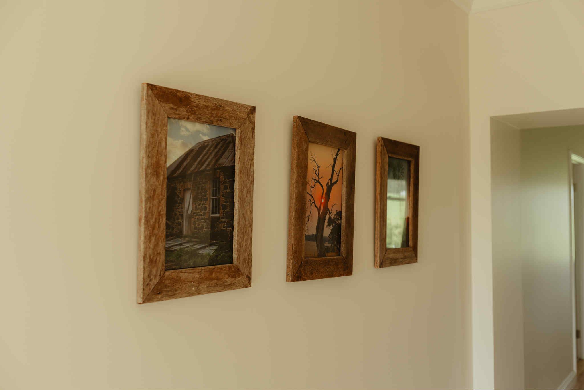 Trois œuvres d’art encadrées sont accrochées à un mur uni.