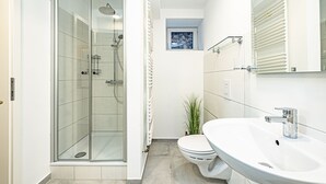 Ett modernt badrum med en dusch som är avskärmad med glasväggar, en toalett och ett handfat.