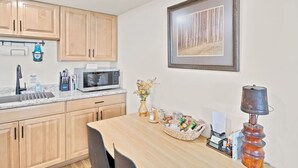 A kitchen with wooden cabinets, a microwave, a sink, and a dining table with chairs.