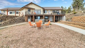 A two-story house with a patio area, outdoor seating, and a stone retaining wall.