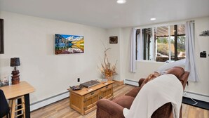 A room with a wooden cabinet, a painting, a window with curtains, and a sofa.