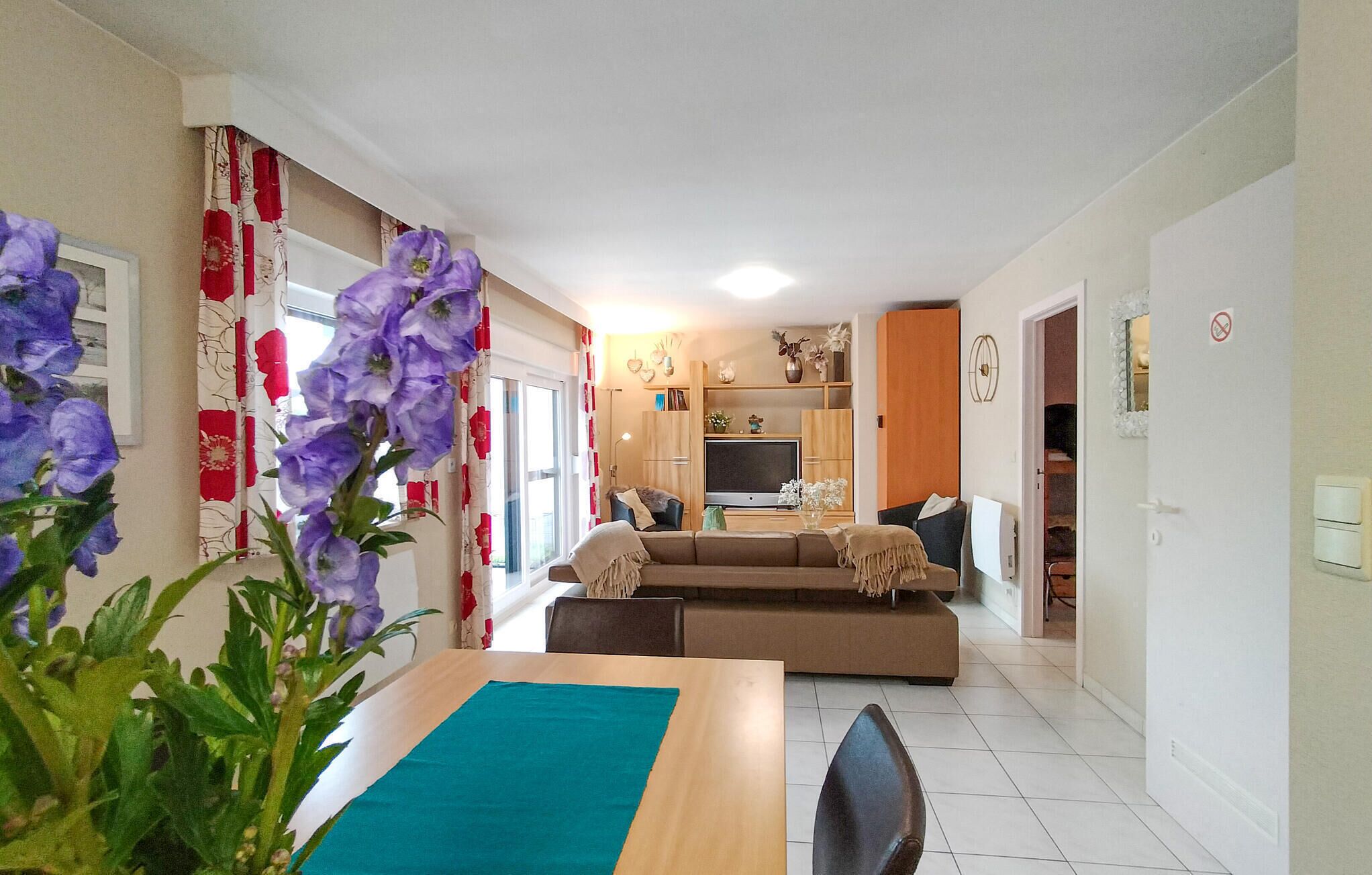 A modern living room with a sofa, a dining table, and a TV.