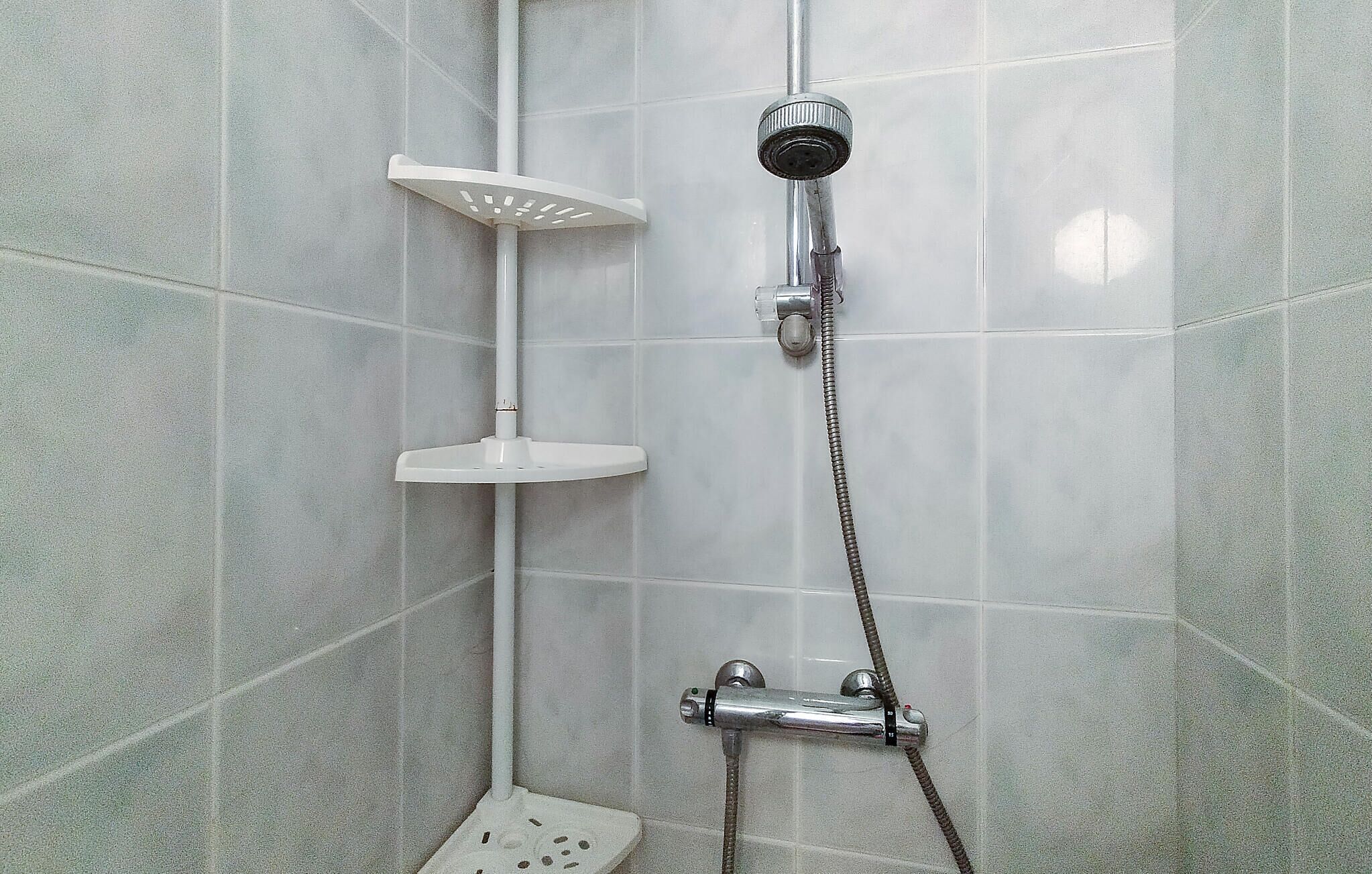 Eine Dusche mit Duschbrause und fest installierter Armatur.