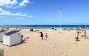 Une plage avec des gens, une tour de surveillance pour les sauveteurs et un panneau indiquant qu'il est interdit de fumer.