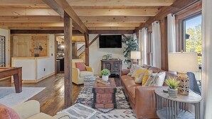 Un salon spacieux avec un plafond en bois, un grand canapé, une table basse et un téléviseur.