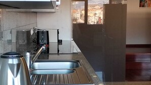 A modern kitchen with a stainless steel kettle, a coffee machine, and a sink.