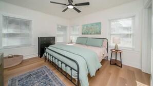 A bedroom with a bed, a ceiling fan, a nightstand, a lamp, and a window with blinds. - Charming 2-bedroom house in Kilgore (Kilgore)