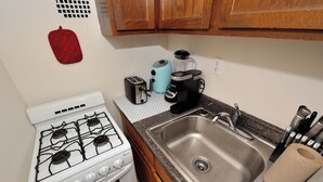 Une cuisine équipée d’une cuisinière à gaz, d’un évier, d’un grille-pain, d’un mixeur et d’une machine à café.