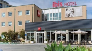 Een hotel met een opvallend 'ibis HOTEL' bord, een terras en een duidelijke ingang.