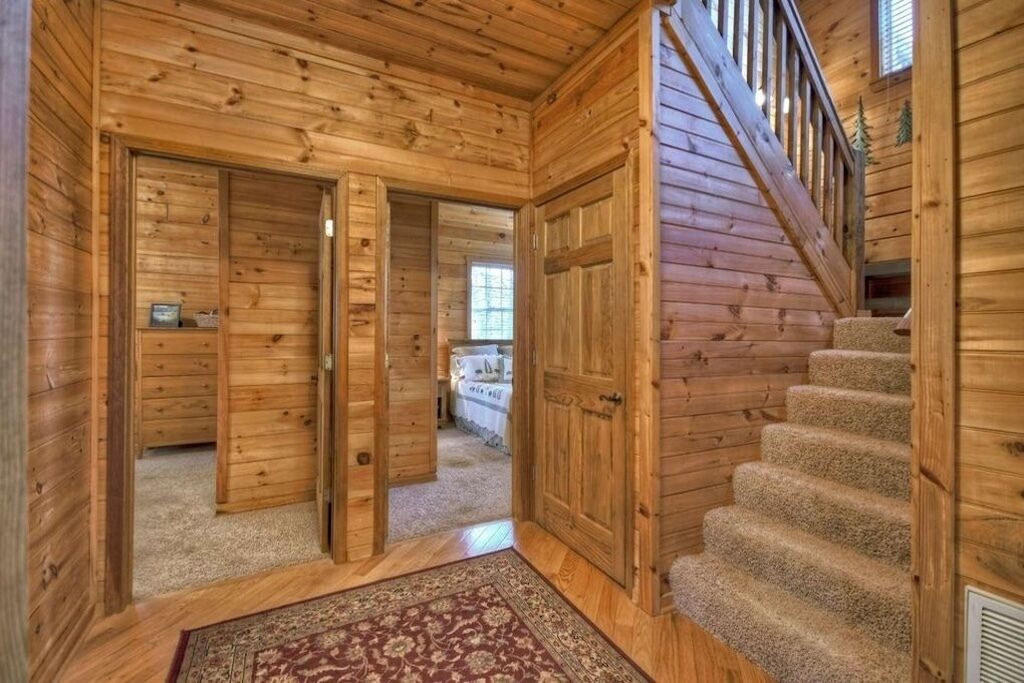 A wooden interior with a carpeted staircase and open doors leading to another room.
