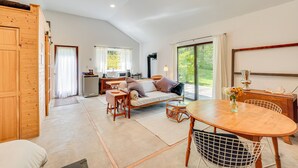 A spacious living area with a sofa, dining table, and kitchen in the background. - 1850s Barn Studio on 4.5 Hudson Valley Acres! (Highland)