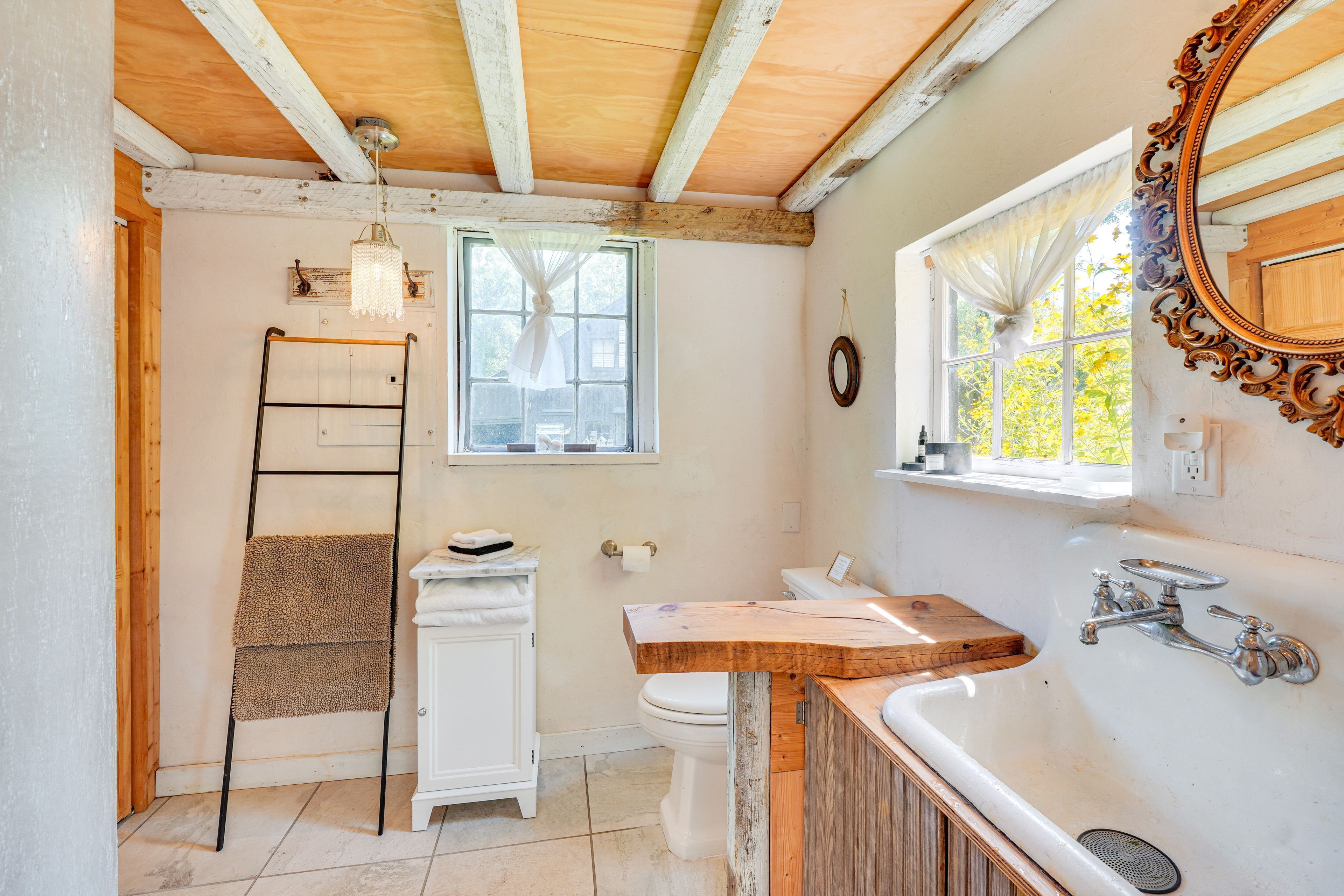 A bathroom with a wooden ceiling, a white sink with a wooden countertop, a white toilet, and a towel rack.