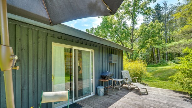 A wooden deck with outdoor furniture, a barbecue grill, and a covered area with an umbrella. - 1850s Barn Studio on 4.5 Hudson Valley Acres! (Highland)