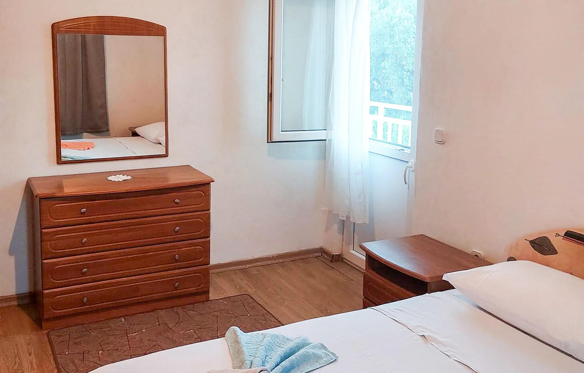 Ein Schlafzimmer mit einem Holzkasten, einem Bett, einem Fenster mit Blick und einem Spiegel an der Wand.