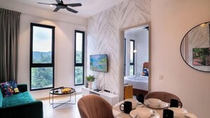 Une chambre d’hôtel moderne équipée d’un canapé, d’une table à manger, de chaises, d’un ventilateur de plafond, d’une télévision et d’une grande fenêtre offrant une vue dégagée.