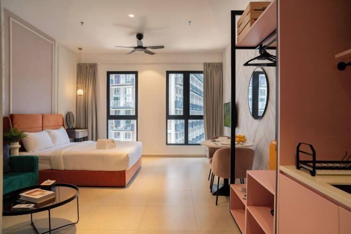 Une chambre d’hôtel moderne équipée d’un lit, d’un bureau, d’une chaise, d’une petite table et d’un ventilateur de plafond.