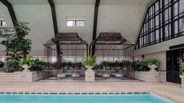 Une piscine intérieure dotée d’un haut plafond, de grandes fenêtres et de plantes en pot.