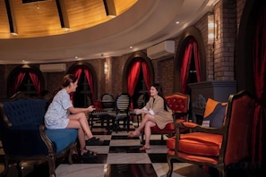 Un salon avec un sol à carreaux, des rideaux rouges et une cheminée.