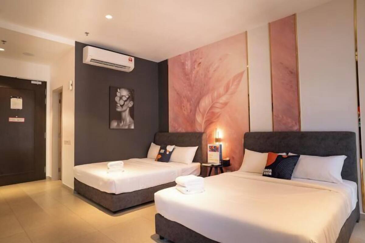 Une chambre d’hôtel avec deux lits, un climatiseur fixé au mur et un tableau.