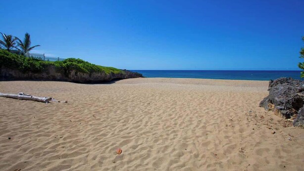 Ein Sandstrand mit blauem Himmel und dem Meer.
