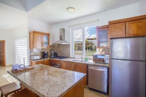 A modern kitchen with granite countertops, stainless steel appliances, wooden cabinets, and a window with a view. - Private Pool Oasis in Sosúa Ocean Village (Sosúa)