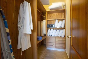 A wooden closet with shelves, a robe, and rolled-up towels. - Private Pool Oasis in Sosúa Ocean Village (Sosúa)