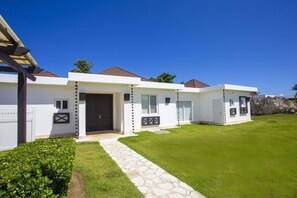 A row of white houses with a stone pathway leading to the entrance, a well-maintained lawn, and a clear blue sky. - Modern 3BR Villa-Private Pool -Sosúa Ocean Village (Sosúa)