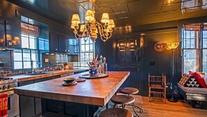 Une cuisine moderne dotée d’un grand îlot central, de tabourets de bar et d’un coin repas avec un canapé et un fauteuil.